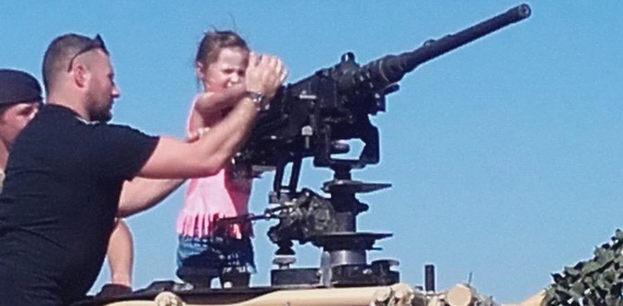 A small child handling a machine gun on Armed Forces Day 2018, Llandudno